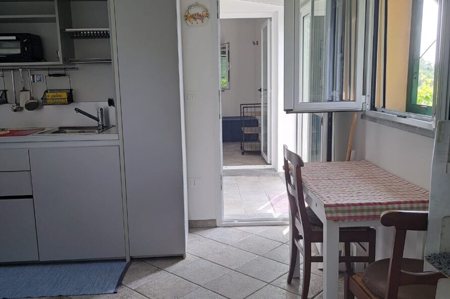 La Casetta della Baronessa — angolo cucina con tavolo e finestra sul verde