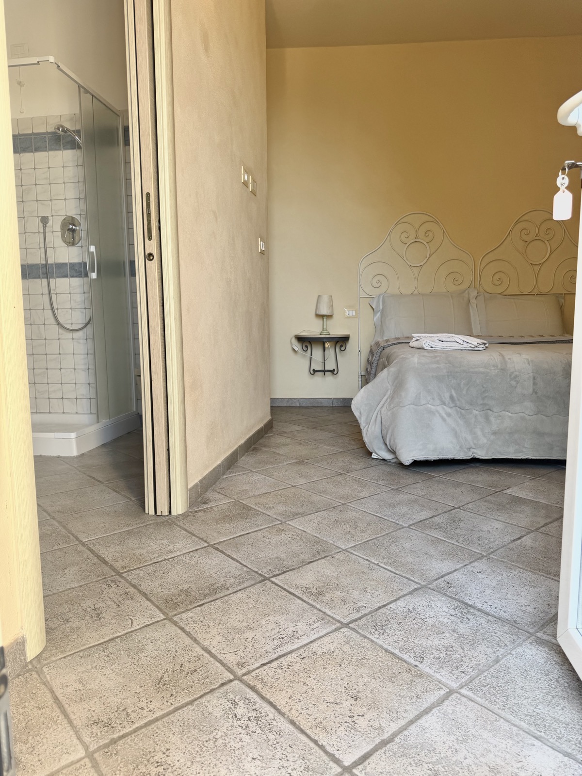 Camera Il Fico — panoramica con letto in ferro battuto e bagno con doccia