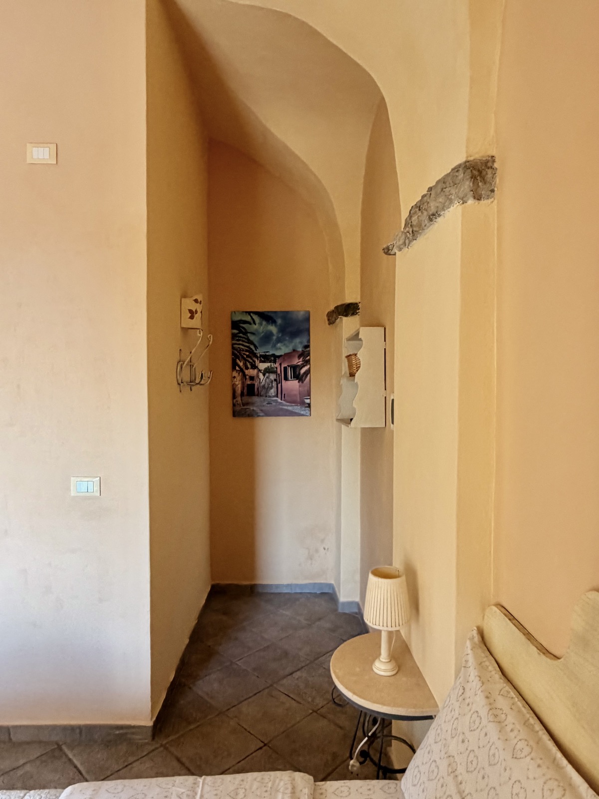 Camera Il Mare — corridoio con archi in pietra e quadro decorativo