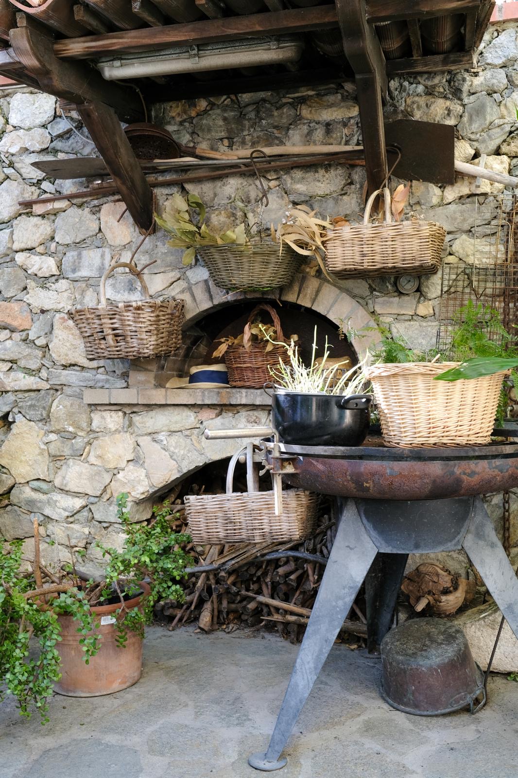 Antico forno in pietra con cesti di vimini e attrezzi contadini