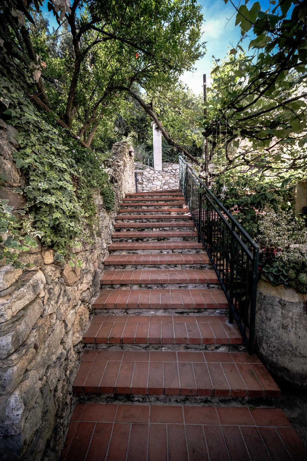 Scalinata in pietra e cotto tra la vegetazione del giardino